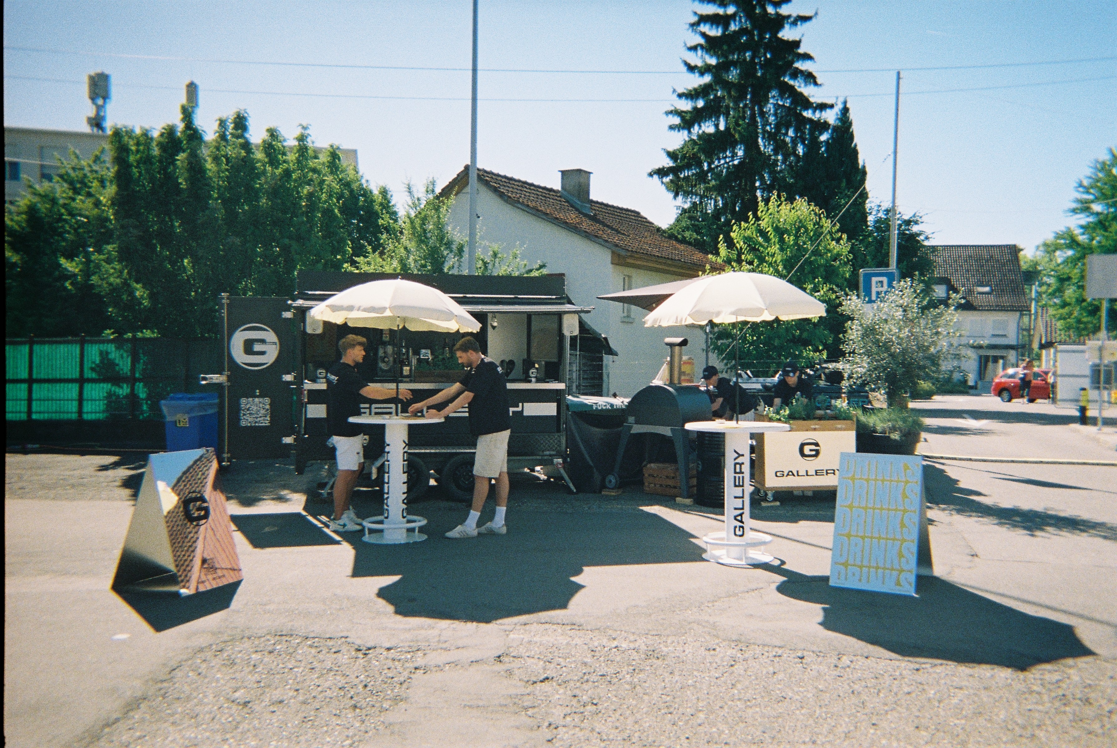Gallery Bar Trailer mit Sonnenschirmen und Stehtischen im Freien