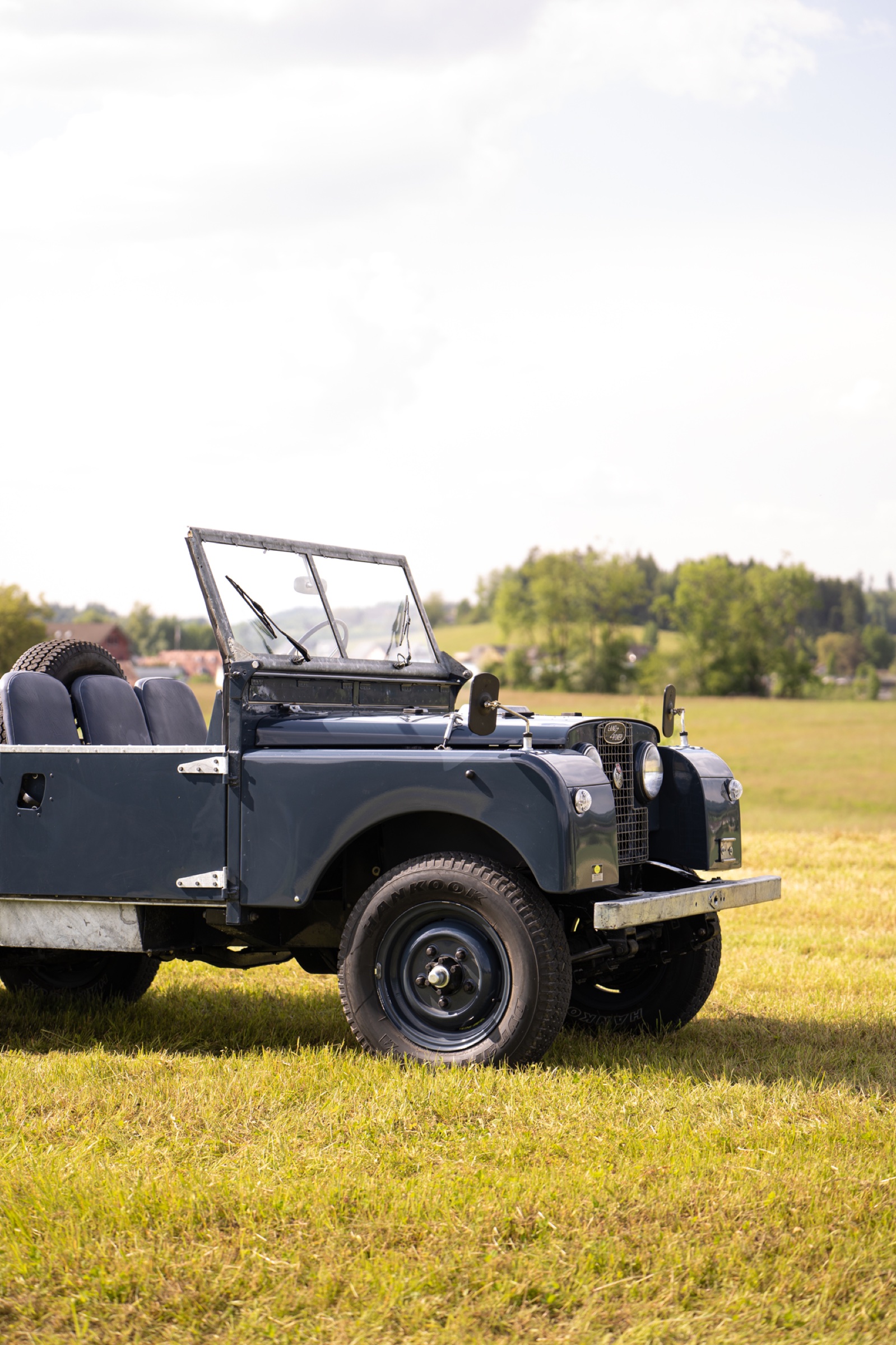 Blauer Land Rover Serie 1 von vorne auf einer Wiese